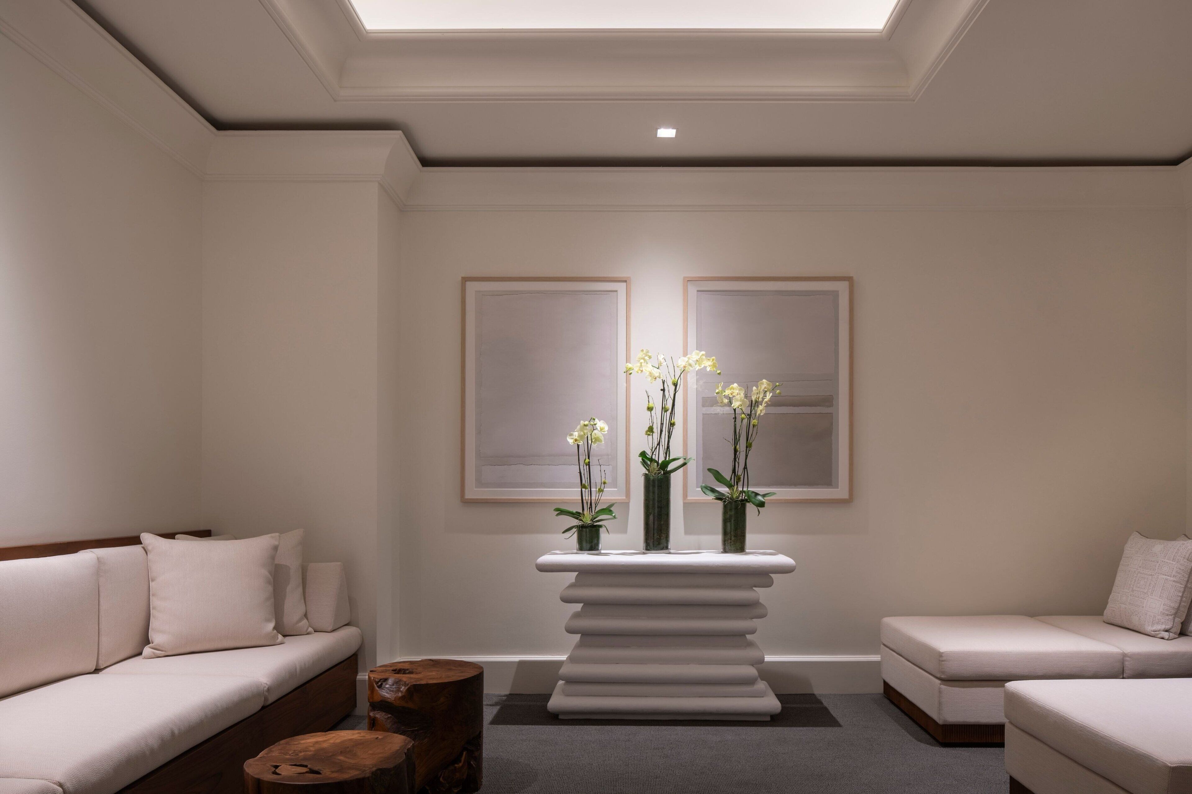 Una habitación moderna y minimalista con sofá, una mesita de madera y un elegante aparador central con jarrones.