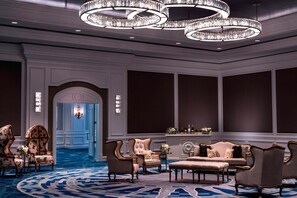 A luxurious lobby with ornate chandeliers, plush seating, and a grand staircase.