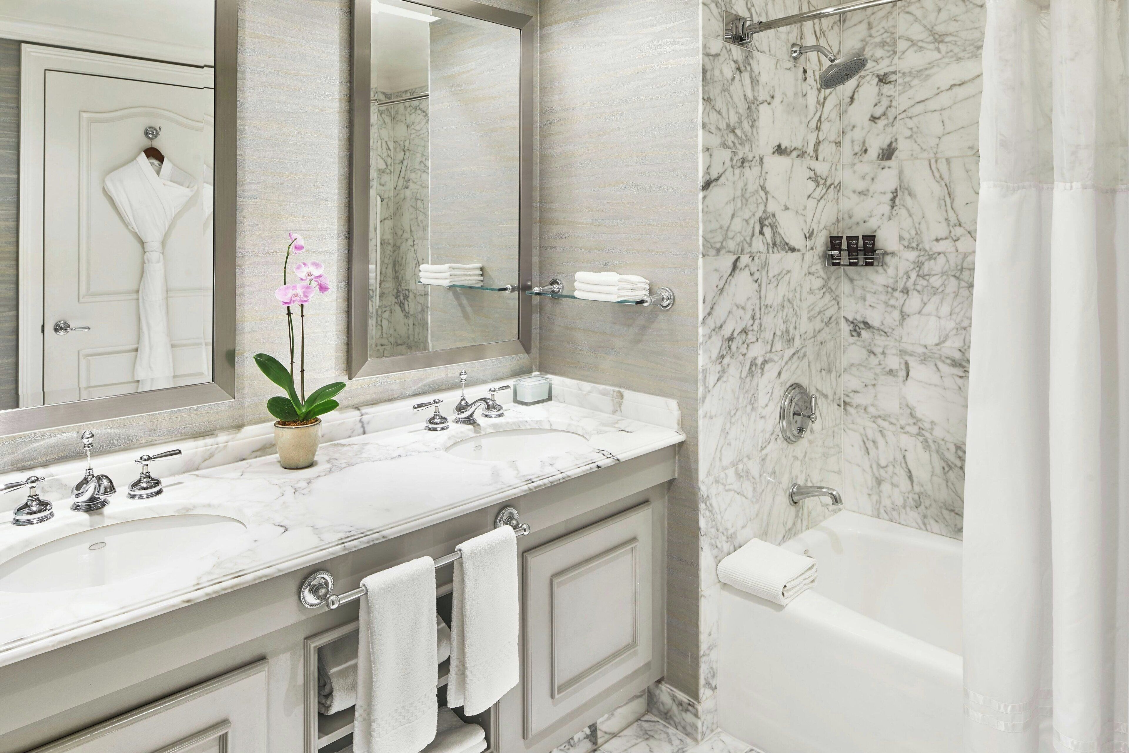 Un baño con lavamanos de mármol, bañera y ducha.