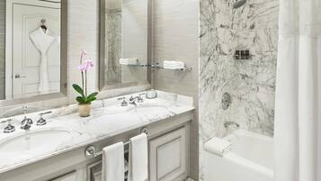 A bathroom with a marble sink, a bathtub, and a shower.