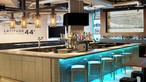 A bar area with a counter, stools, and a variety of bottles. - Four Points by Sheraton Halifax (Halifax)