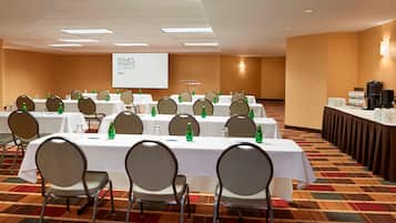 A conference room with multiple tables, chairs, and a presentation screen.