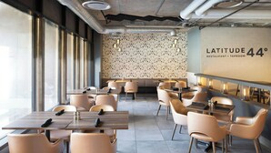 A modern restaurant interior with a patterned wall, wooden tables, and beige chairs. - Four Points by Sheraton Halifax (Halifax)