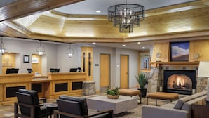Un hall d’entrée avec un comptoir de réception, un espace salon, une cheminée et un plafond en bois.