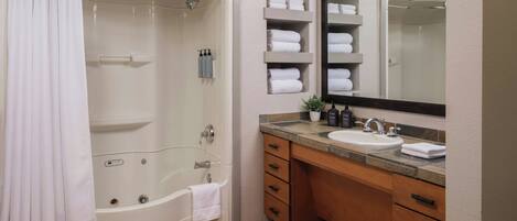 Un baño moderno con una bañera, una ducha, un lavabo y un espejo grande.