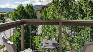 A balcony with two chairs, a small table, and two cups of coffee.