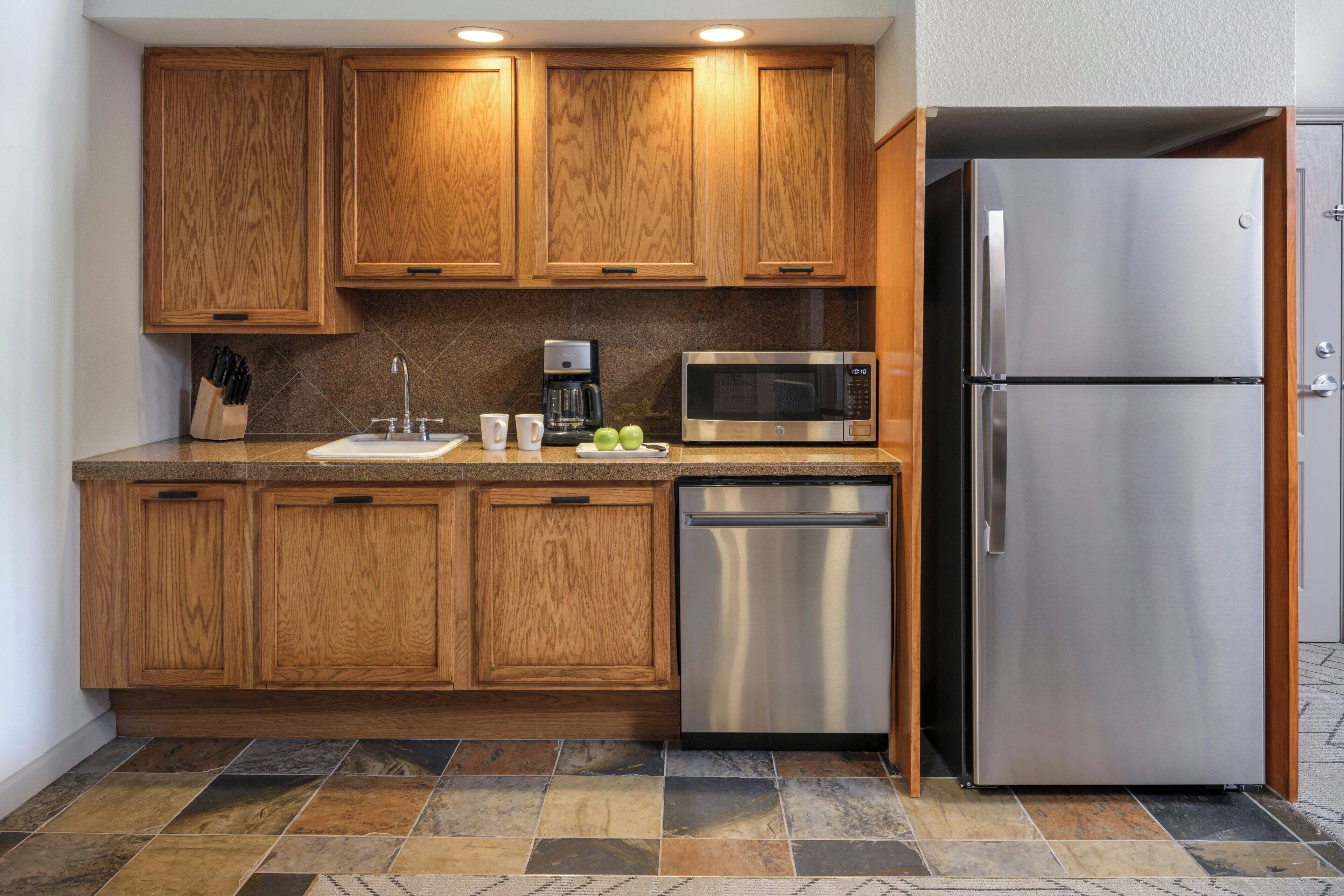 A kitchen with wooden cabinets, a stainless steel refrigerator, a microwave, and a dishwasher.
