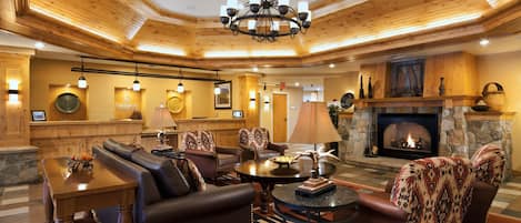 A spacious living room with a fireplace, leather sofas, and a chandelier.