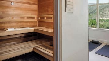 A sauna room with wooden benches and a wall-mounted thermometer.