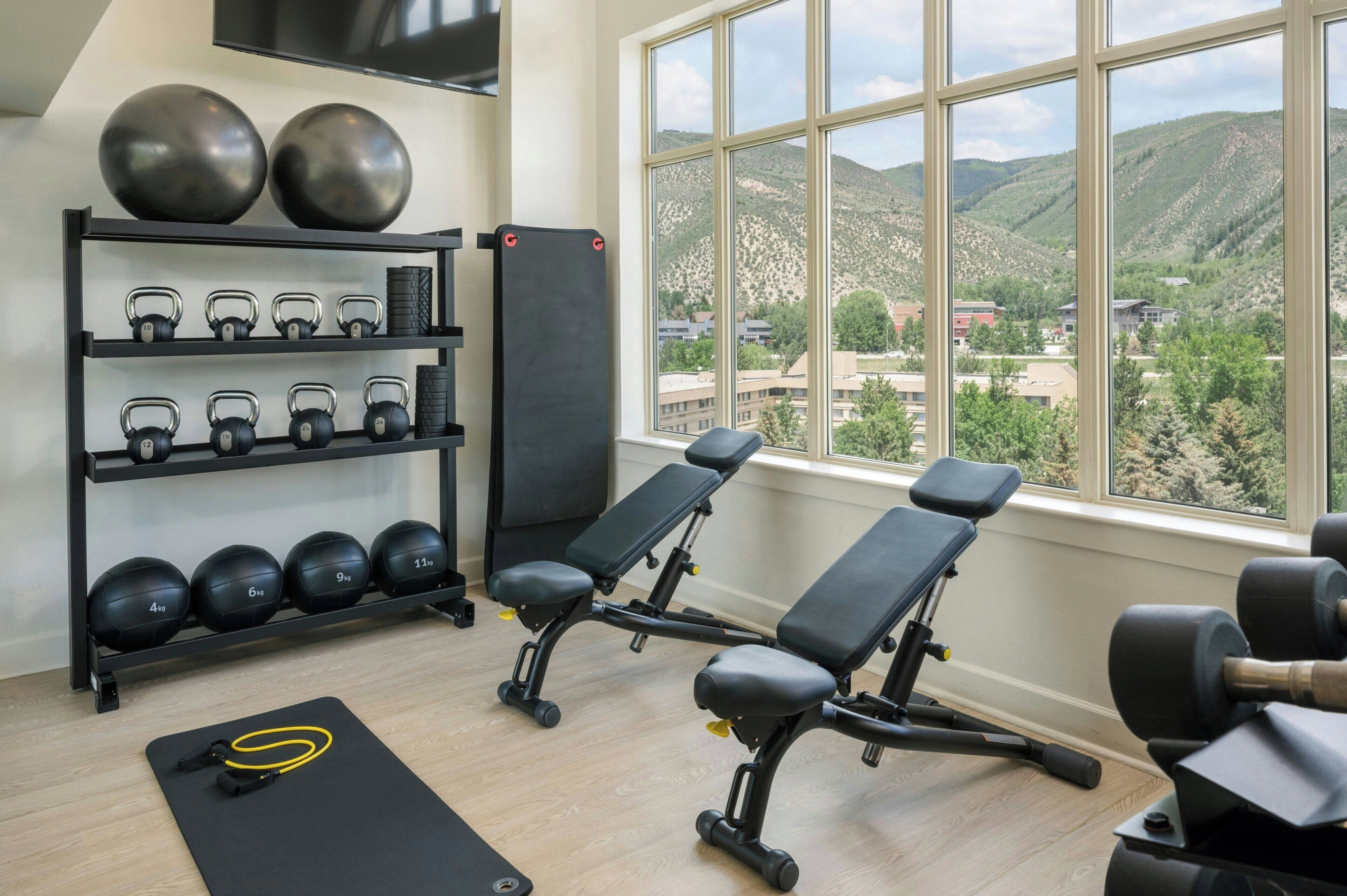 A gym with kettlebells, dumbbells, and exercise benches.