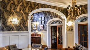 Un lobby espacioso con paredes de mármol, elegantes candelabros y muebles clásicos.