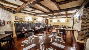 Un restaurante con vigas de madera, cabinas de cuero y una larga mesa dispuesta para comer.