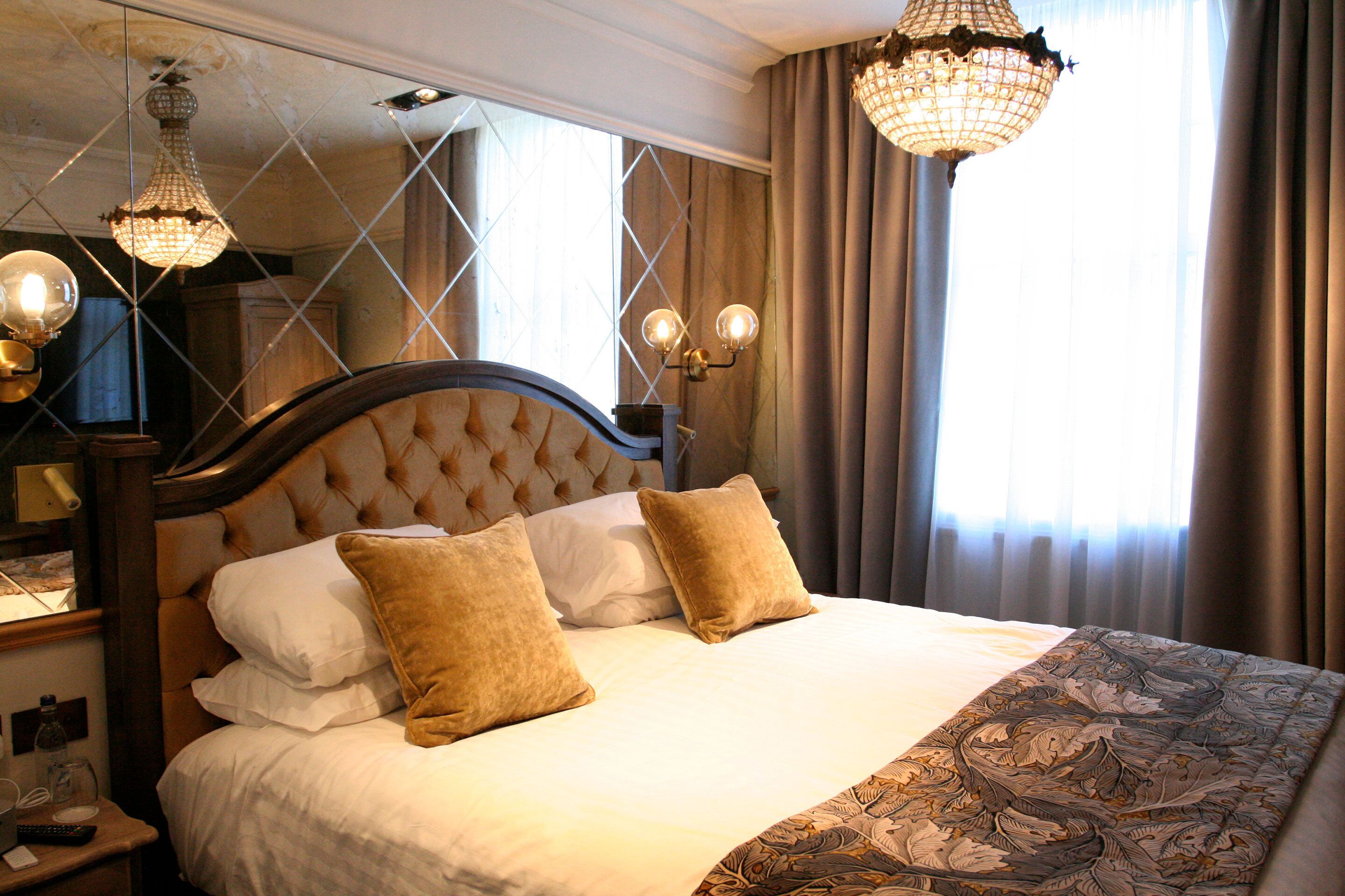 A neatly made bed with a wooden headboard, two pillows, and a patterned throw blanket.