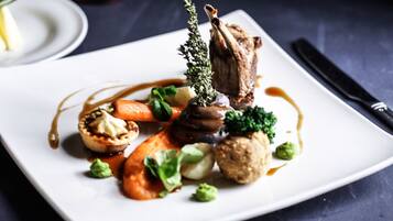 A white plate with a variety of food items including a piece of meat, vegetables, and a small tart.