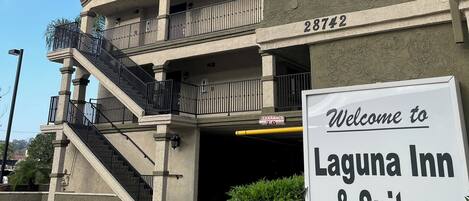 A building with a sign reading "Welcome to Laguna Inn & Suites" and a parking area with directional arrows.