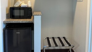 A compact kitchenette with a microwave, a small refrigerator, and a metal drying rack. -  Laguna Inn & Suites (San Juan Capistrano)