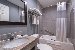 A modern bathroom with a granite sink, a white toilet, a bathtub, and a shower curtain. -  Laguna Inn & Suites (San Juan Capistrano)