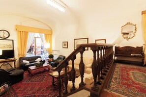 A living room with a staircase, a sofa, a coffee table, and a television. - Hotel Rex (Florence)
