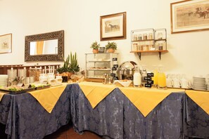 A breakfast buffet setup with a variety of food items, a mirror, and decorative plants. - Hotel Rex (Florence)