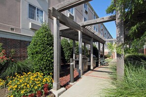 Un espace extérieur abrité, doté d’une pergola en bois, d’un barbecue et d’un banc.