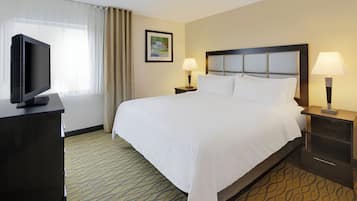 A hotel room with a large bed, two bedside lamps, a television on a desk, and a framed picture on the wall.