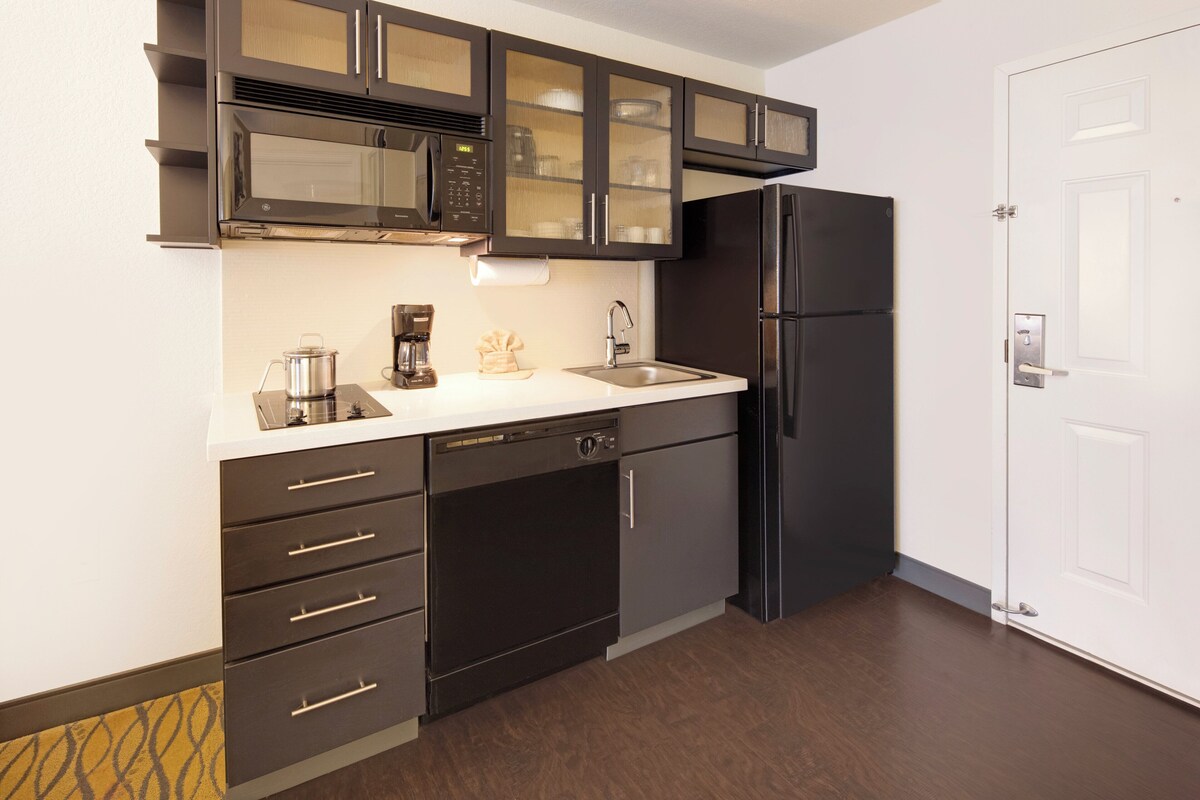 Una cocina moderna con armarios oscuros, un refrigerador de acero inoxidable y un microondas.