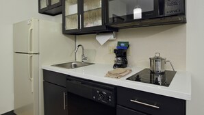 A modern kitchen with a refrigerator, dishwasher, microwave, stove, and sink. - Candlewood Suites Rogers / Bentonville by IHG (Rogers)