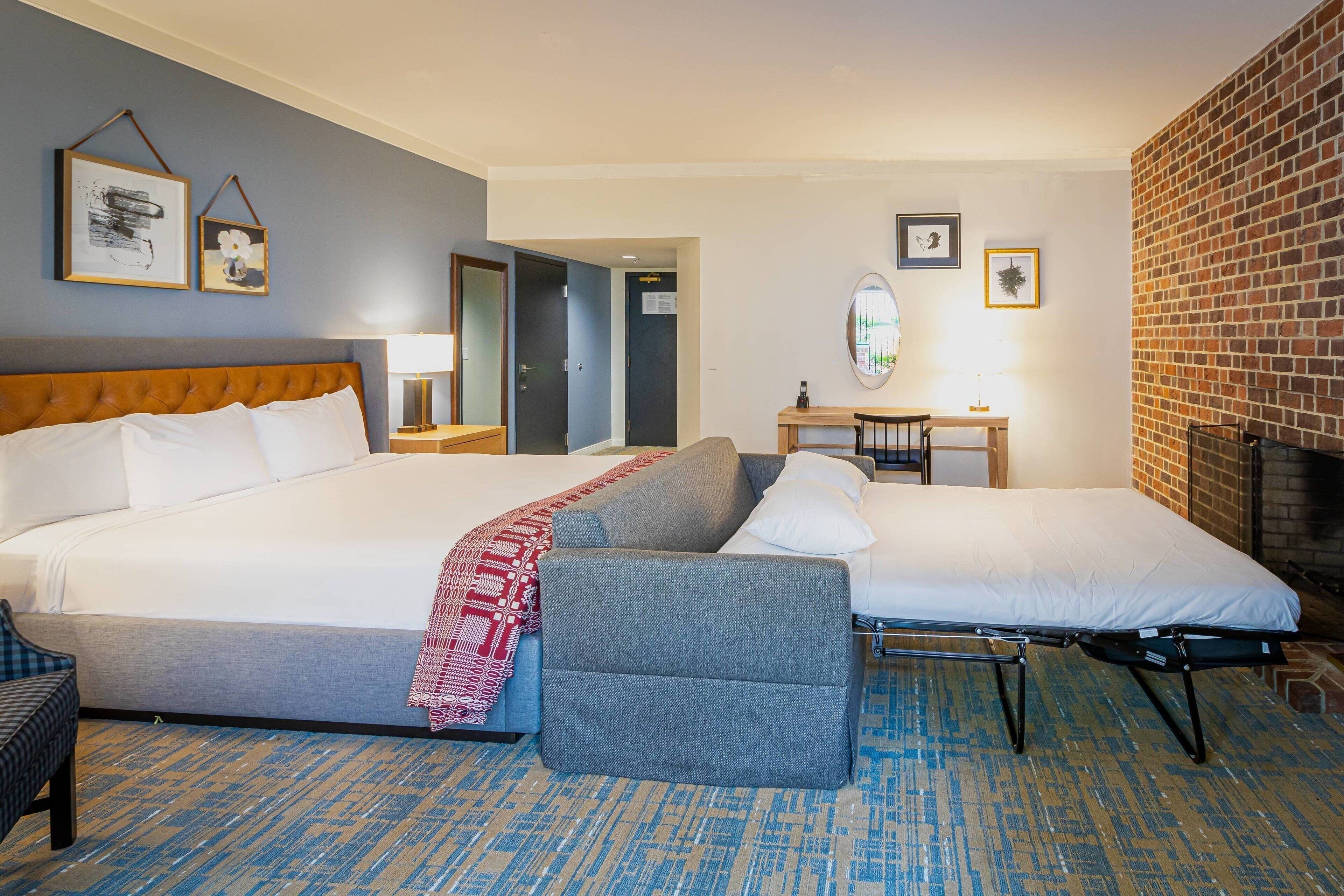 Una habitación de hotel con una cama grande, un sofá, un escritorio y una chimenea.