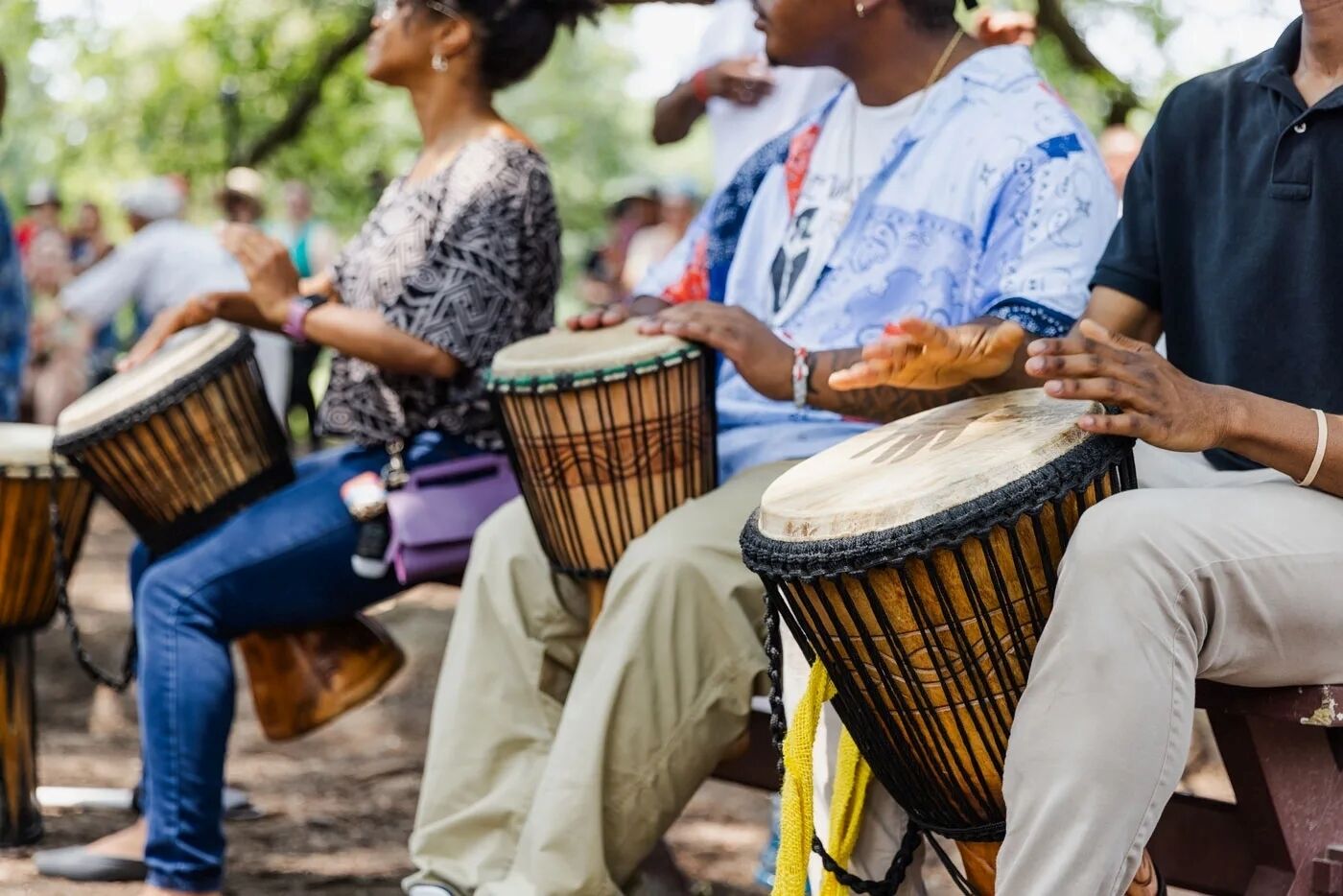 People seated outdoors playing drums.