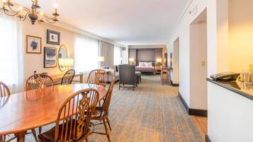 A hotel room with a dining area, a living room, and a kitchenette.
