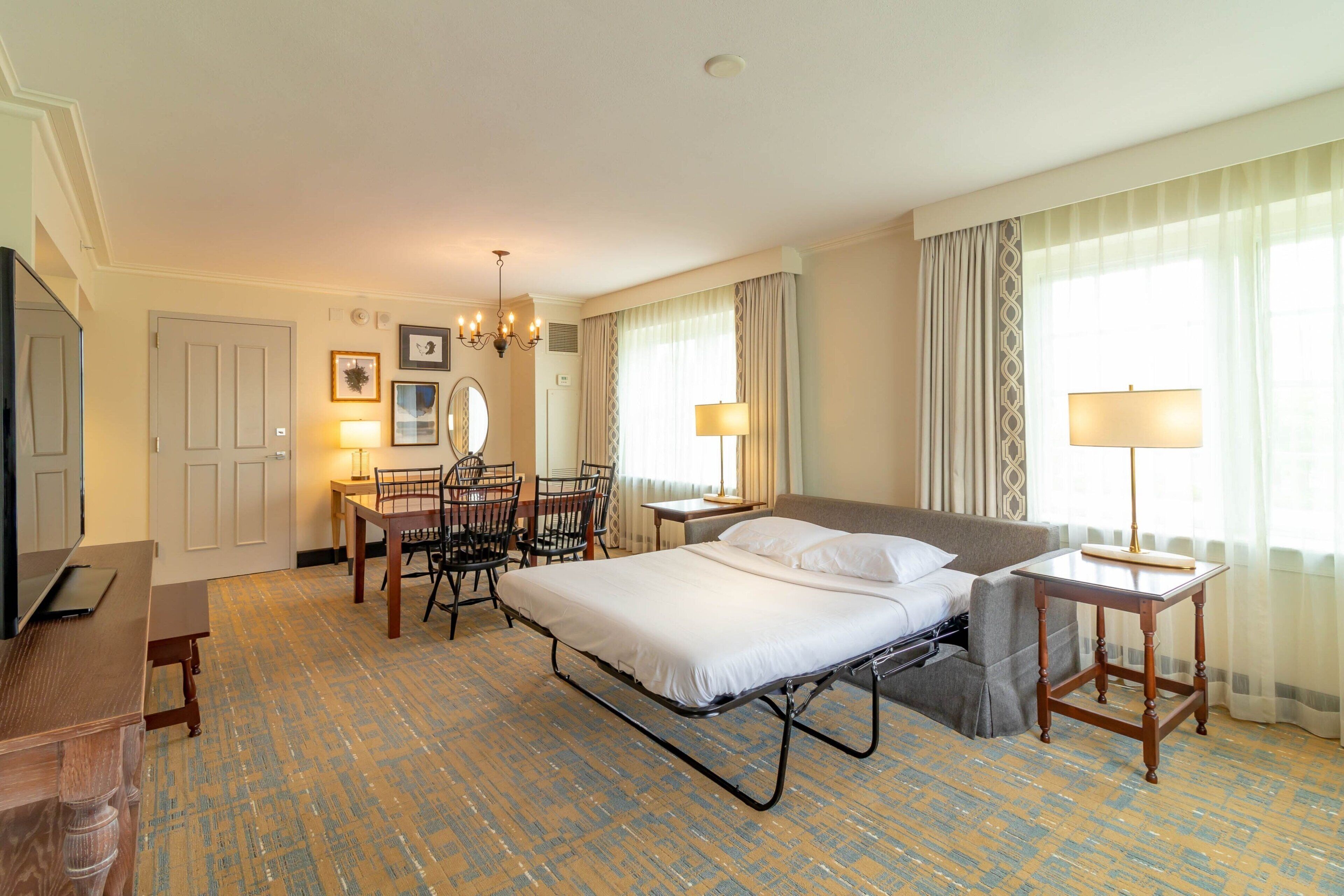 Een hotelkamer met een bed, een bureau, een stoel, een lamp en een televisie.