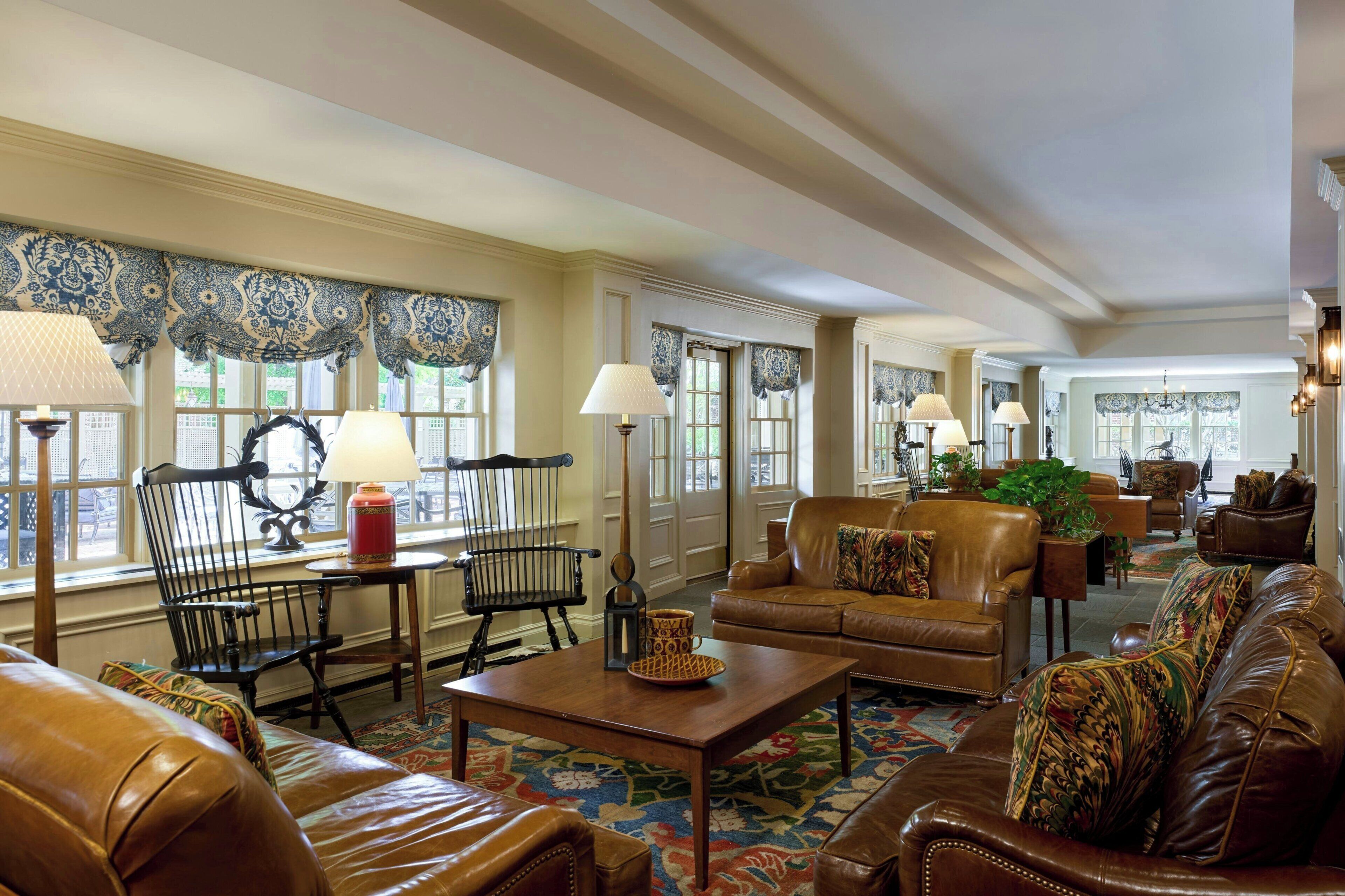 A spacious living room with leather sofas, a coffee table, and a patterned rug.