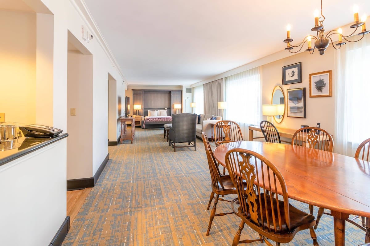 A hotel room with a dining area, a bed, and a bathroom.