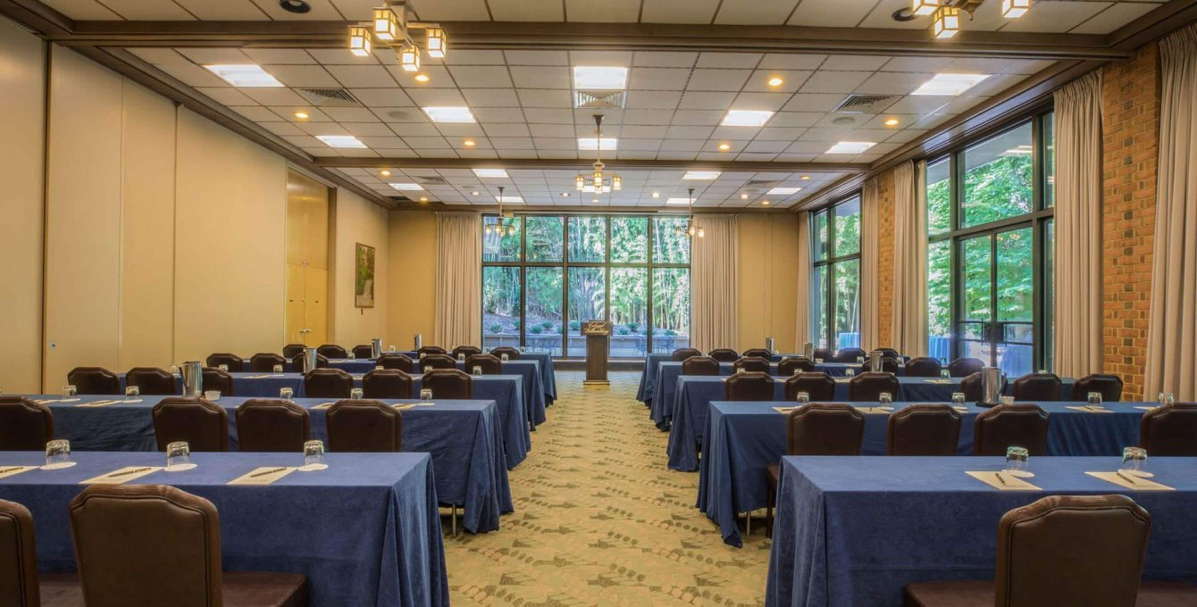 A conference room with rows of tables, chairs, and a podium.