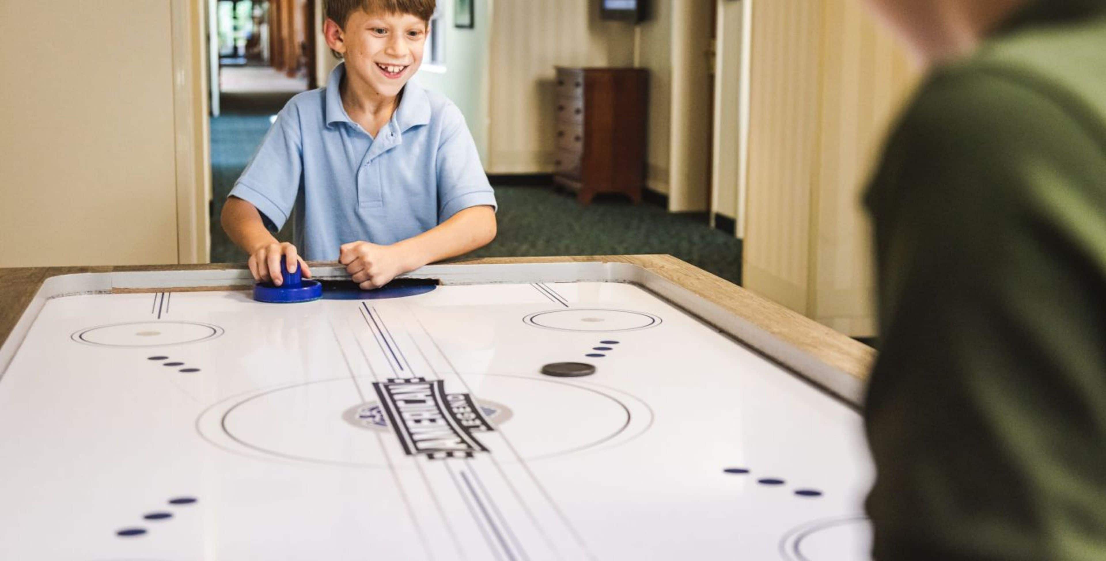 A person playing shuffleboard at a hotel table.