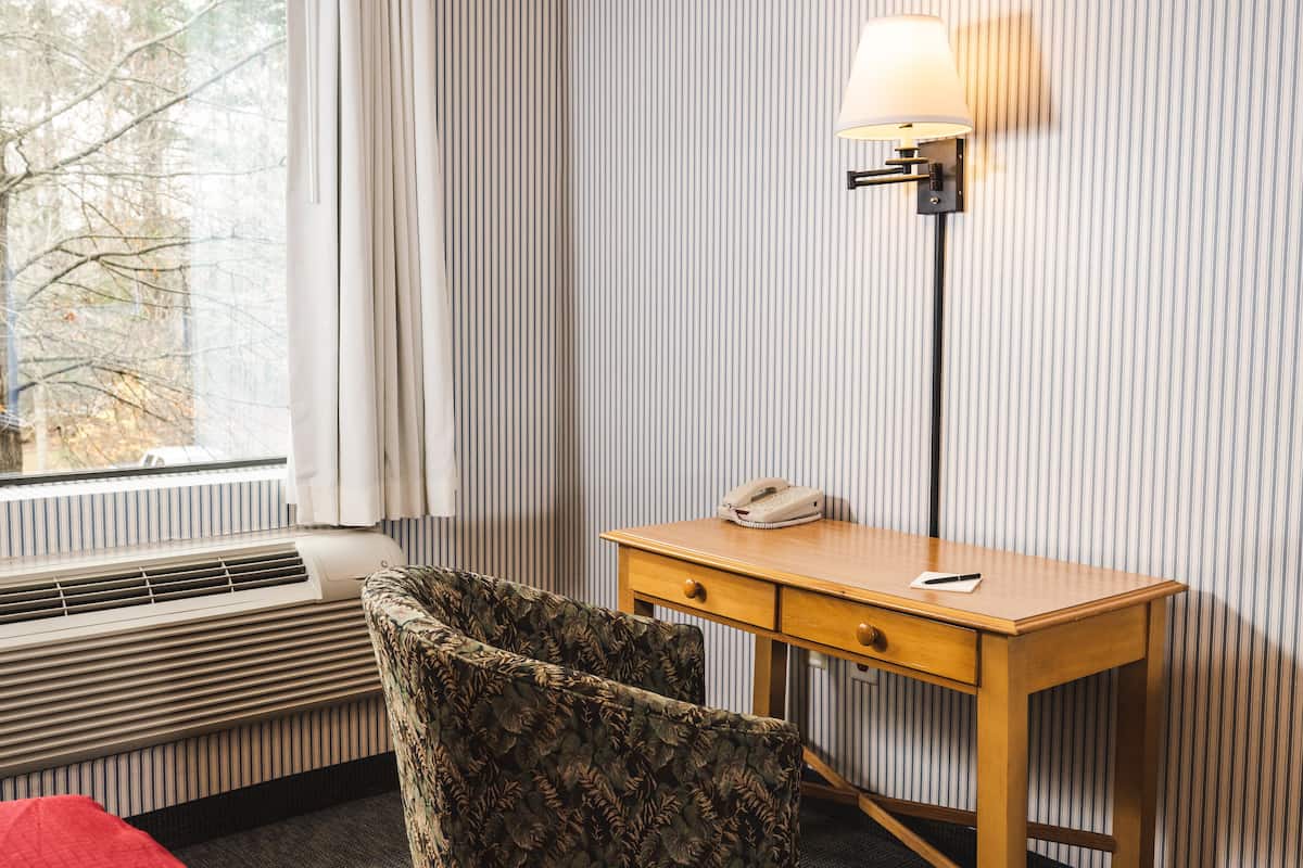 Une chambre d’hôtel avec un bureau en bois, un téléphone et une lampe.