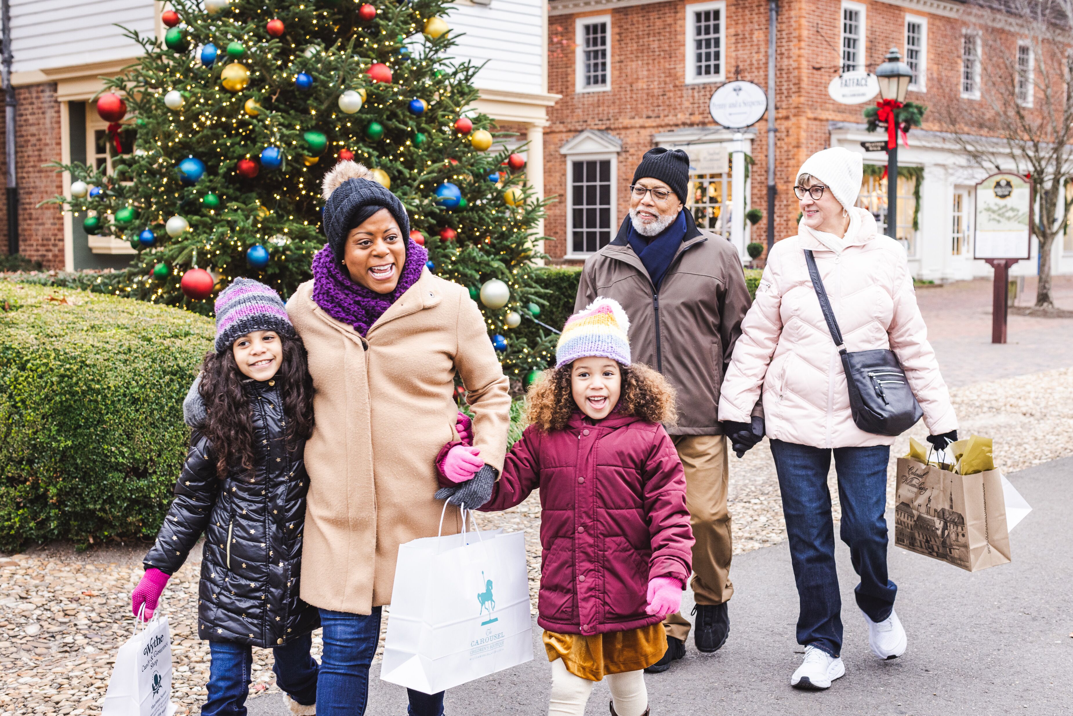 Una familia caminando junto a un árbol de Navidad con adornos coloridos.