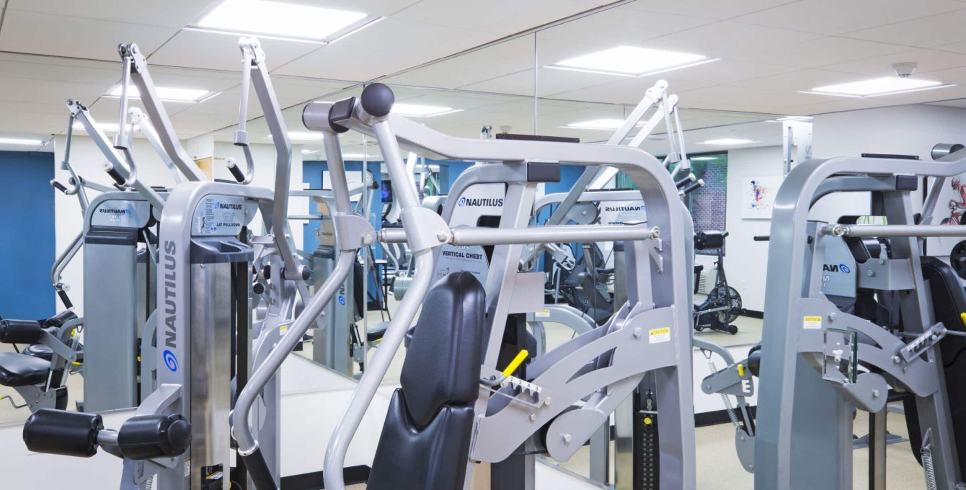 A gym with Nautilus equipment, mirrors, and a blue wall.