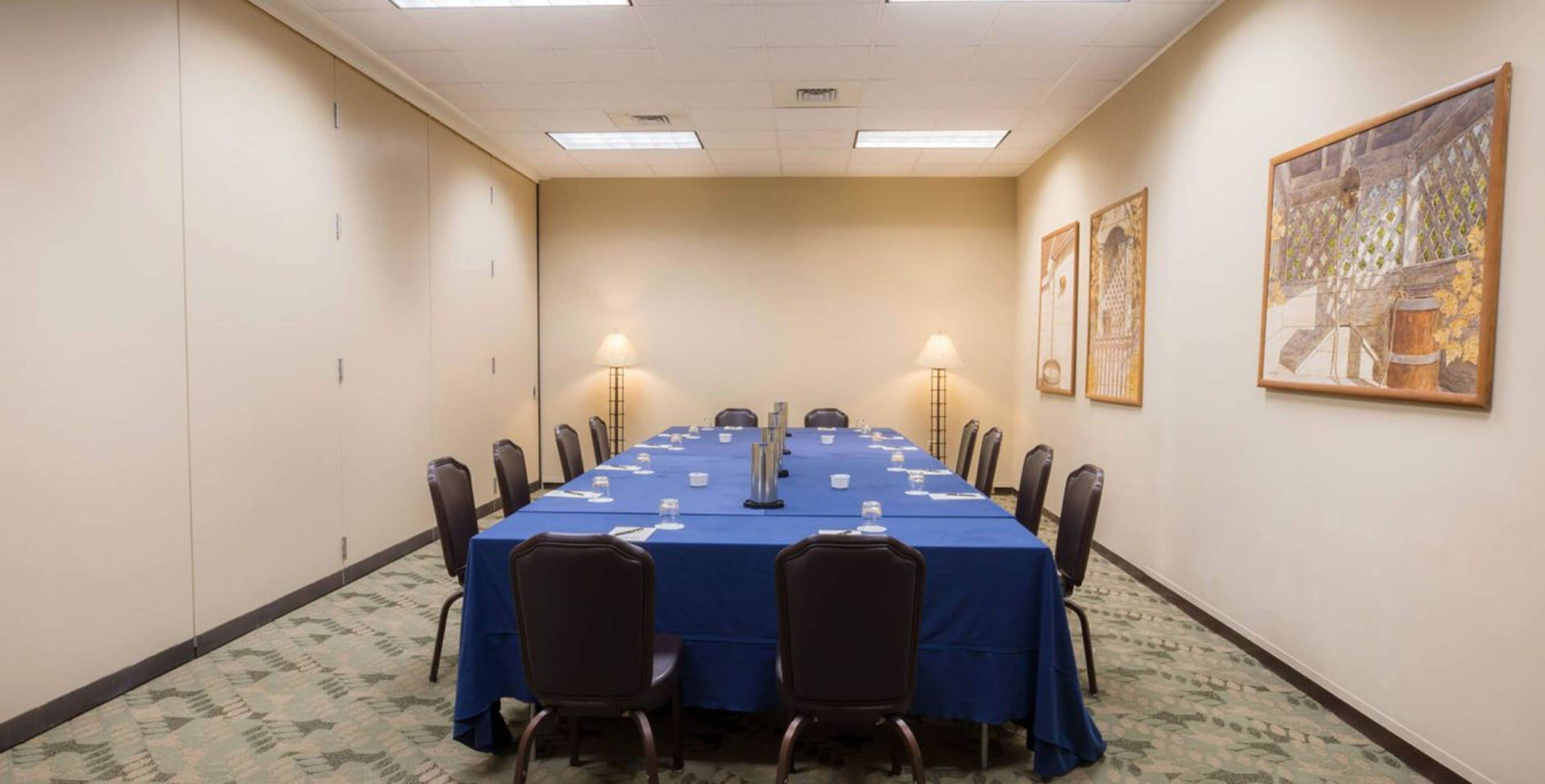 A conference room with a long table, chairs, and two lamps.