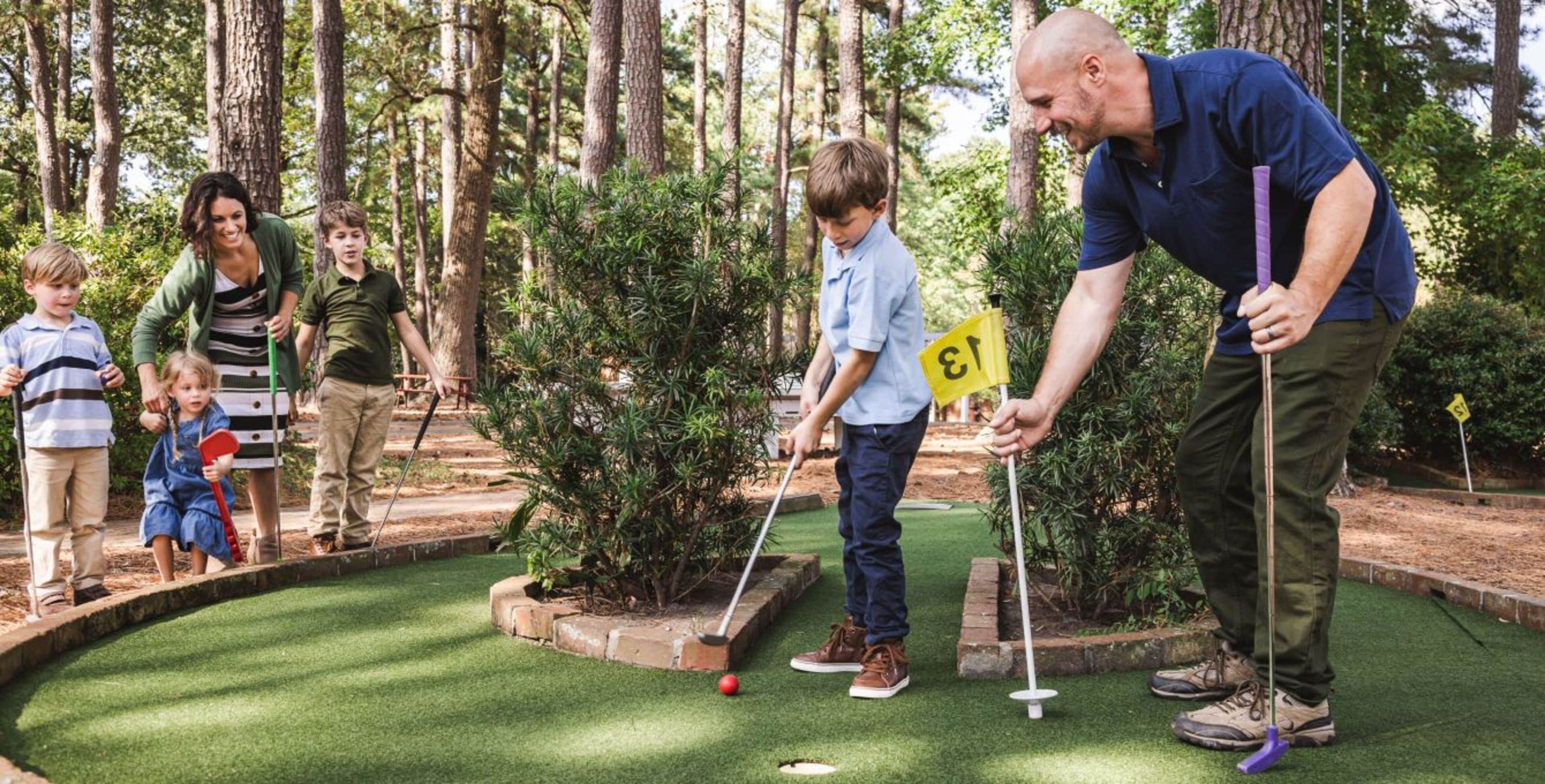 En miniatyrgolfbana med spelare och en caddie.
