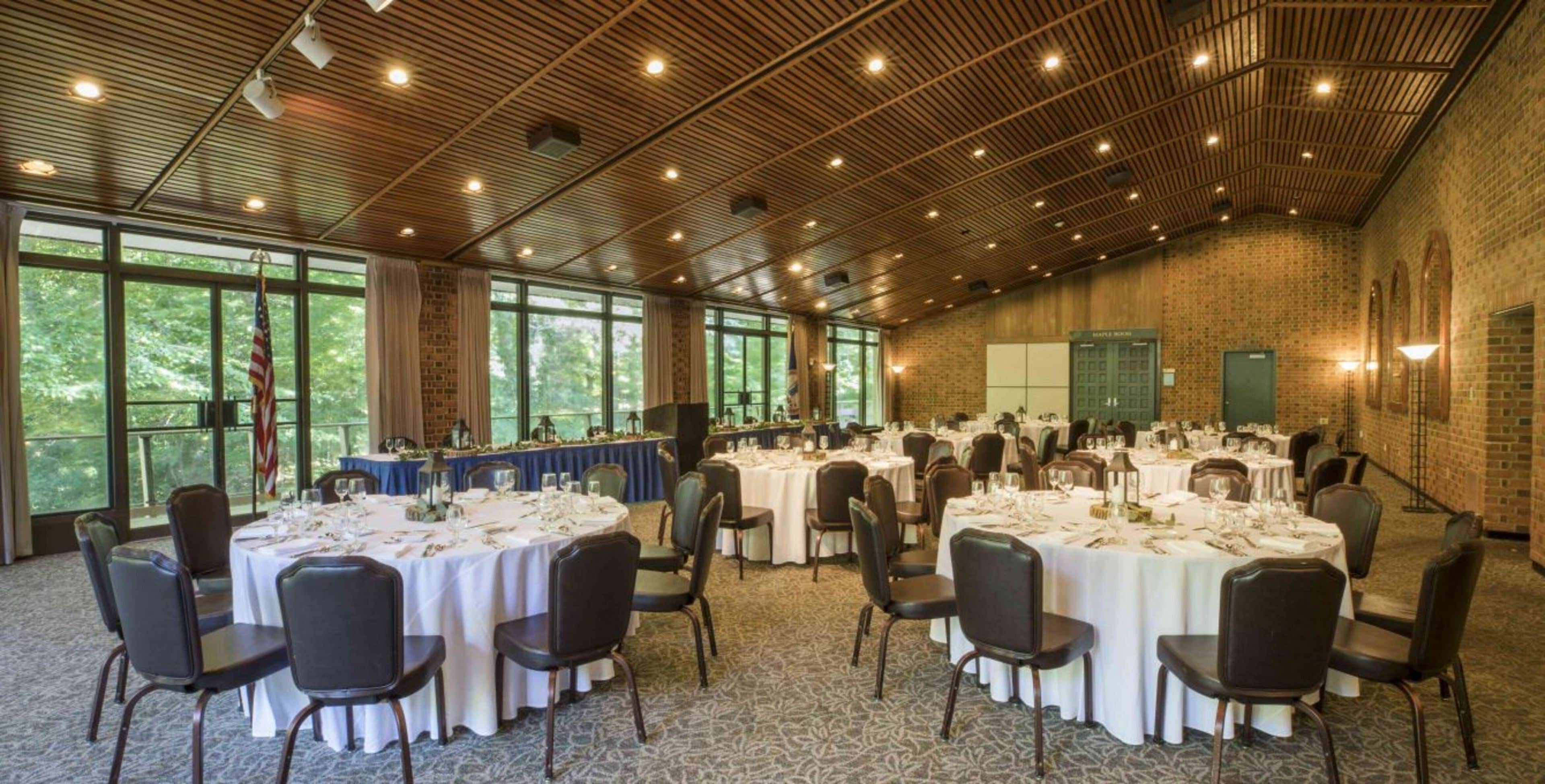 Un grand espace de restauration intérieur avec des tables rondes, des chaises et un mur en briques.