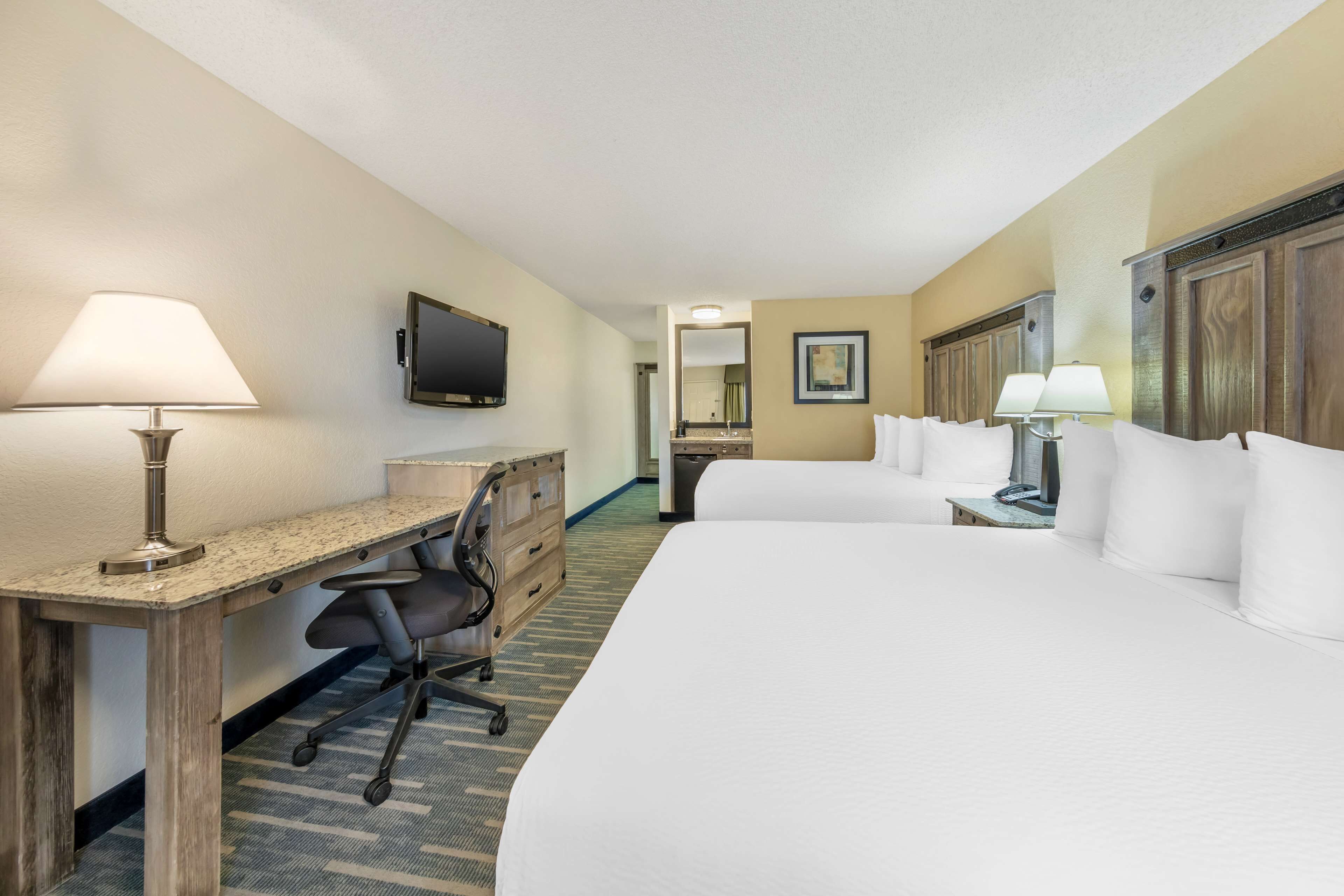 Una habitación de hotel con cama, escritorio, silla y lámparas.