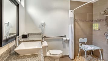 A bathroom with a white sink, toilet, and shower area.