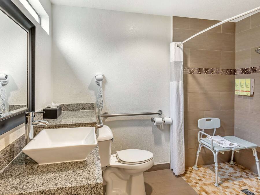 A bathroom with a white sink, toilet, and shower area.
