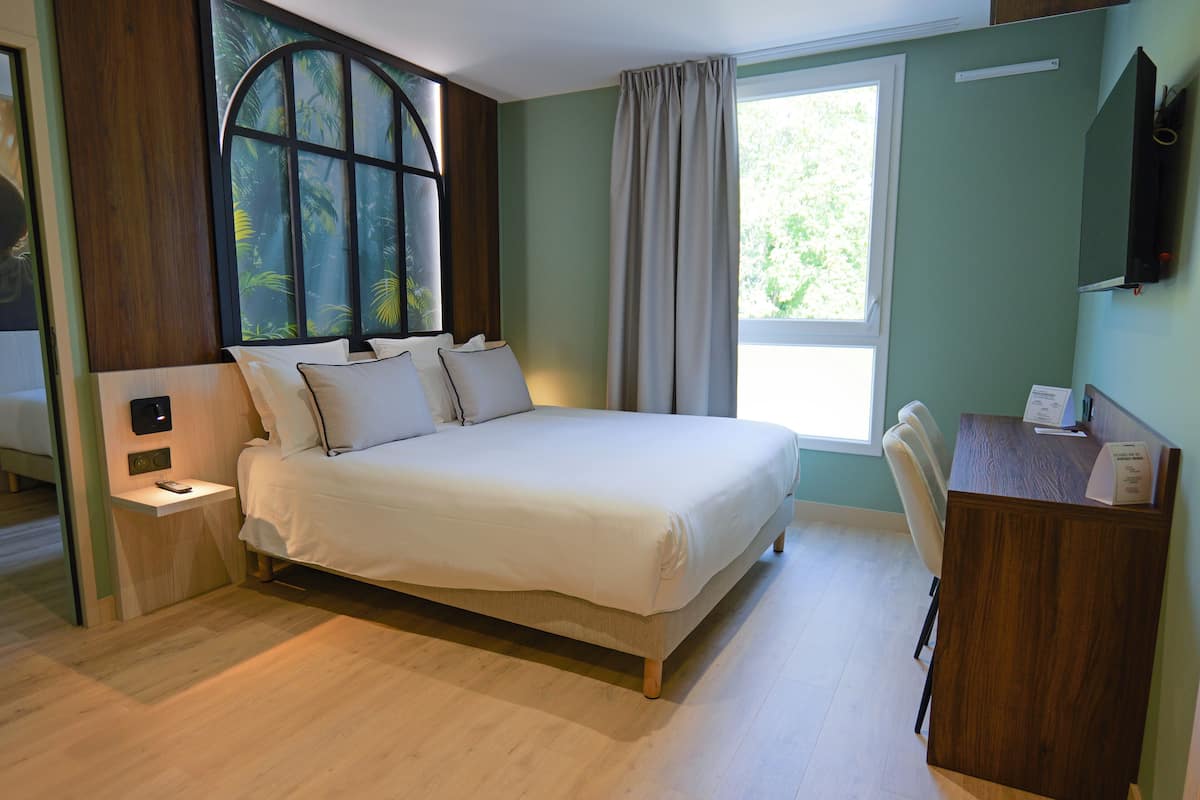 Een slaapkamer met een bed, een bureau en een raam.