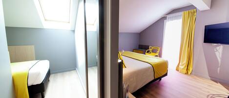 A bedroom with a bed, a desk, a chair, a TV, and a window.