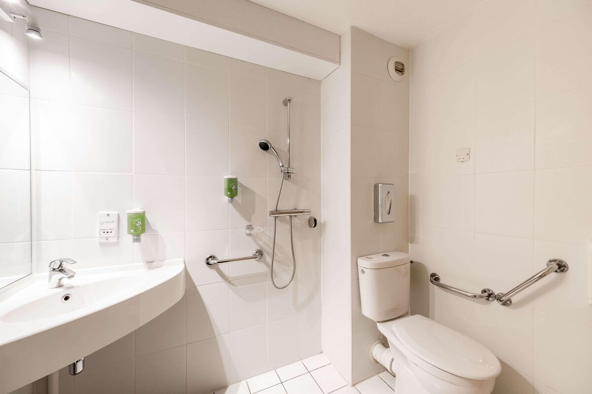 Un baño moderno con lavamanos, inodoro y ducha.