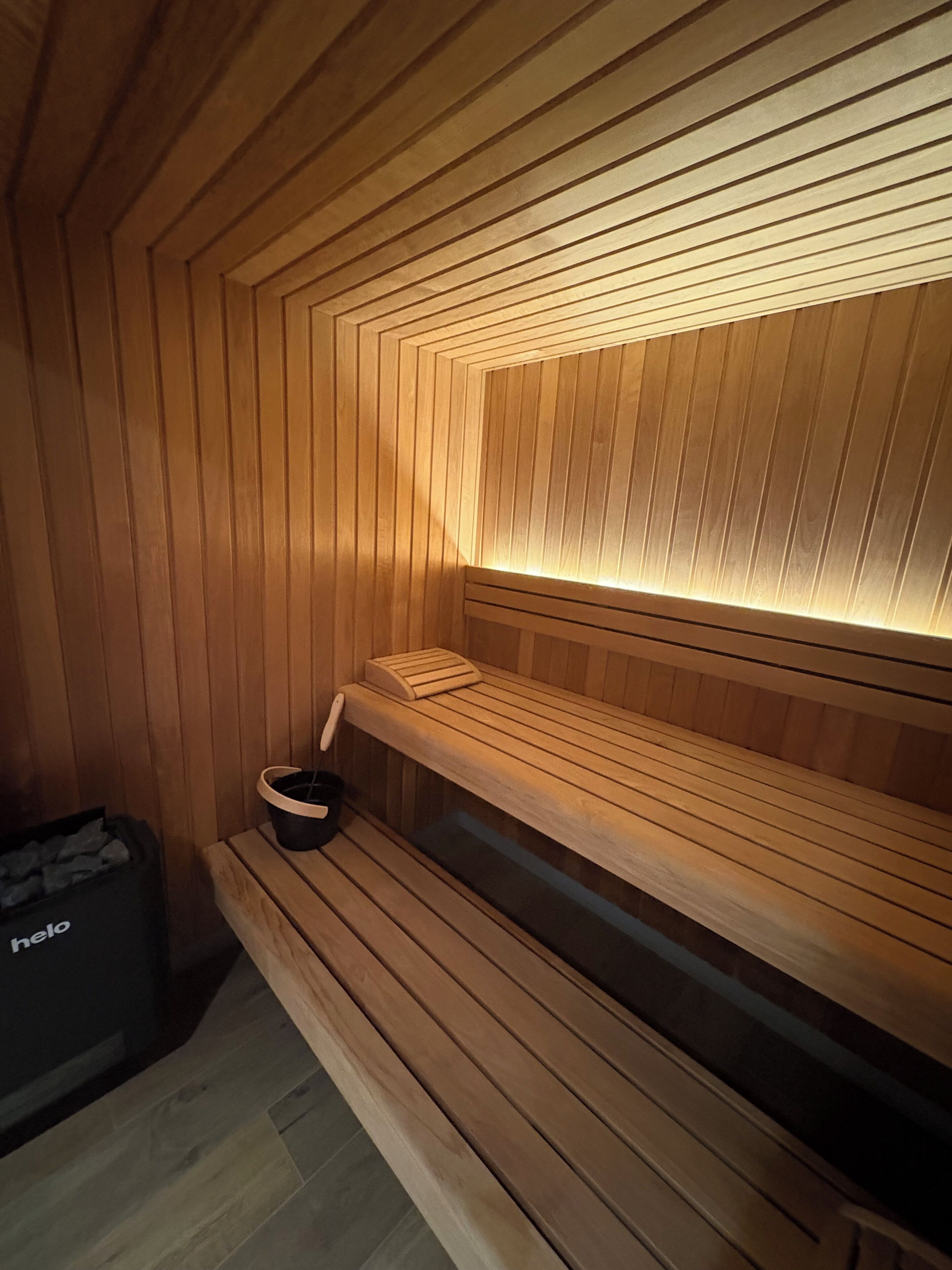 Una sauna con bancos de madera y un balde.