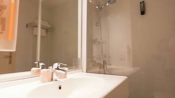 A bathroom with a white sink, a mirror, and a shower.