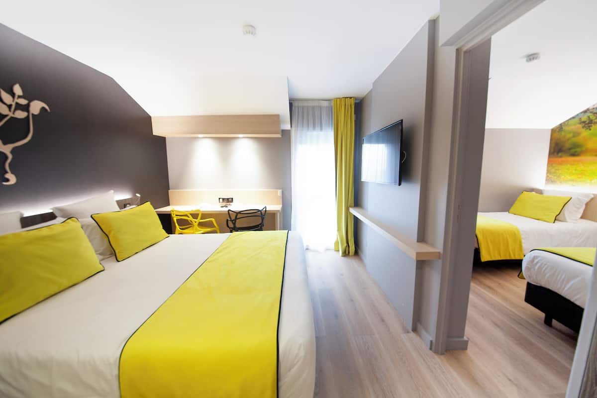 A hotel room with a large bed, a desk, and a television.